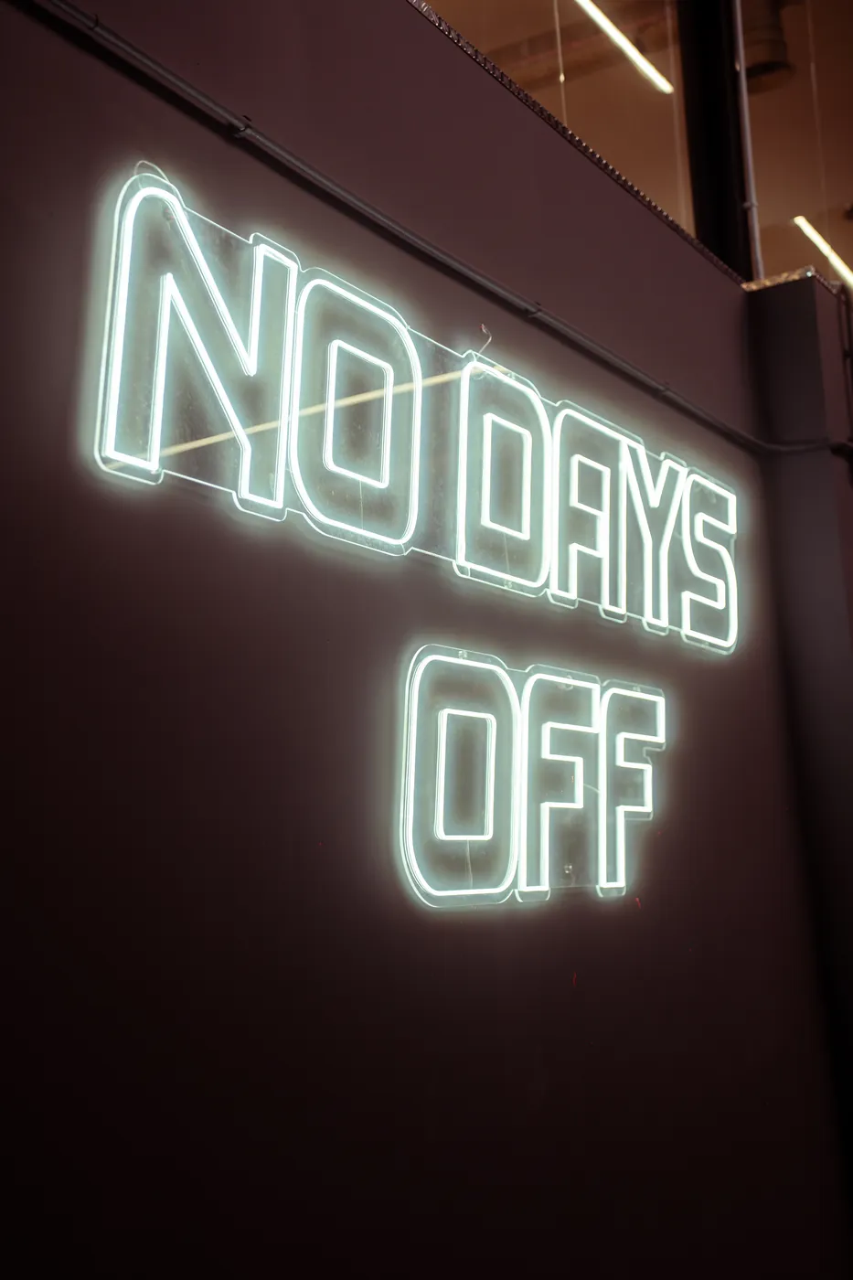 Neón NO DAYS OFF en la pared del club